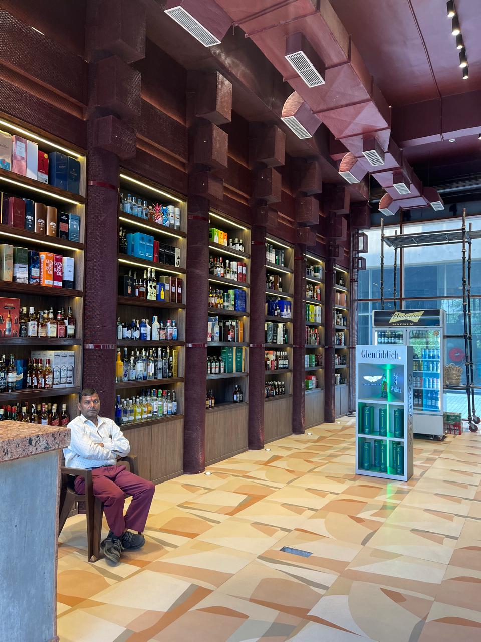 Air-conditioned retail theka in Noida featuring premium whisky, wine, and beer brands